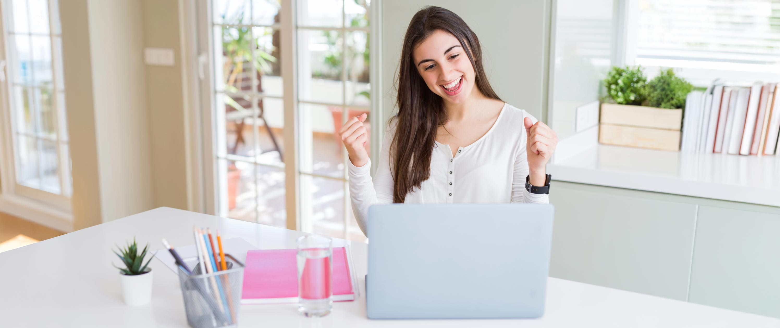 A person with their hands up looking at a computer